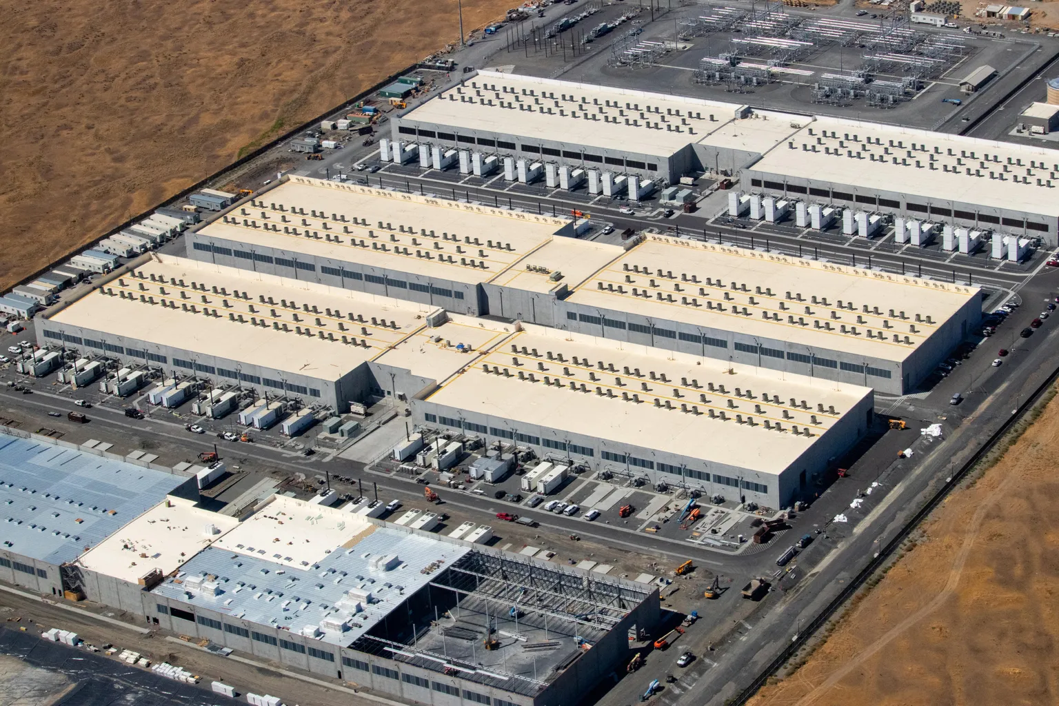 Aerial view of multiple Amazon Web Services data-center buildings in the us-west-2 region, including a building under construction.