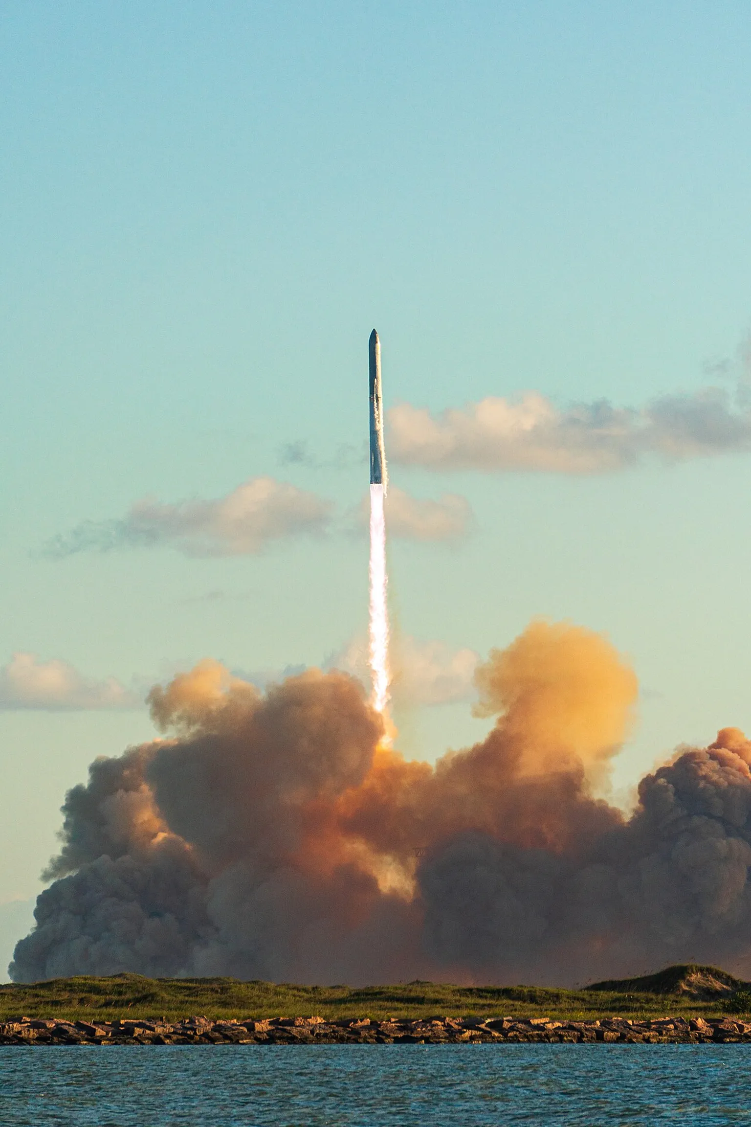SpaceX Starship rises above clouds and launch-site smoke during Flight 11 at Starbase in October 2025.