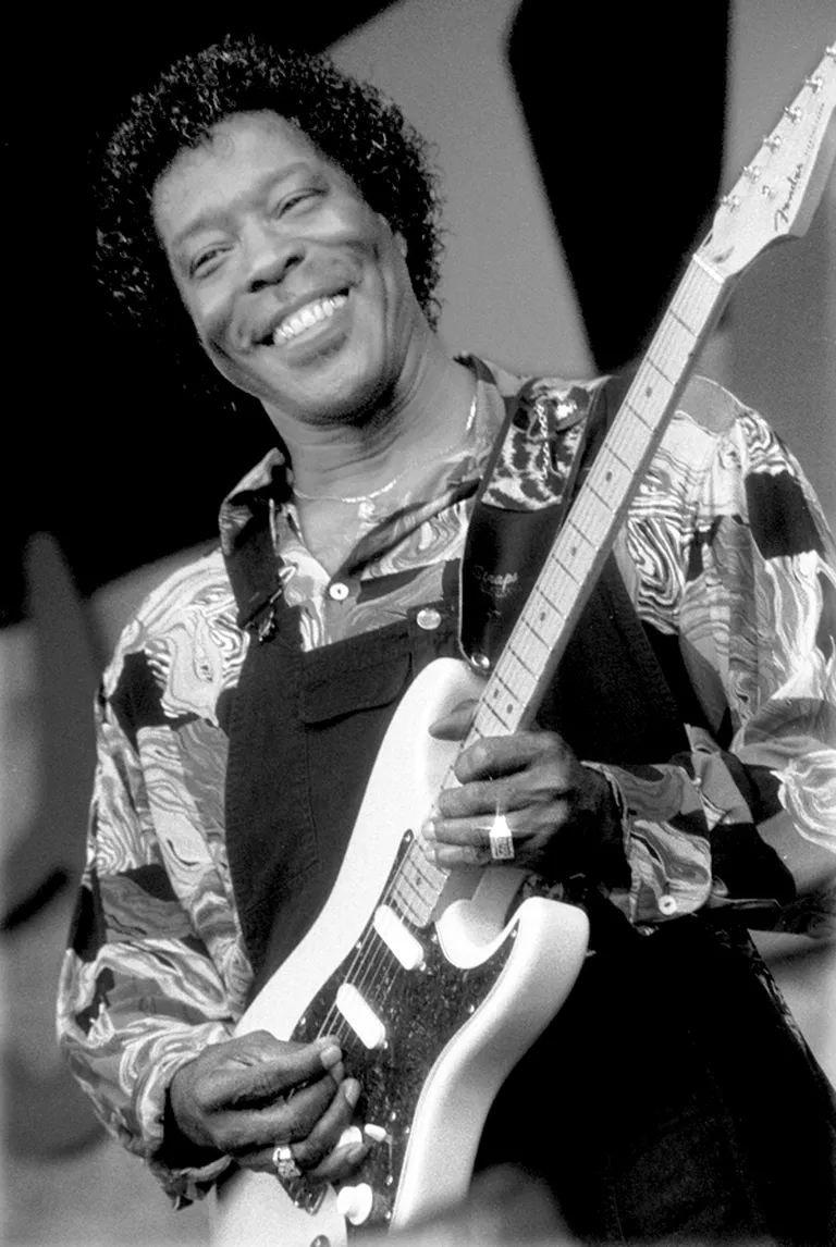 Buddy Guy smiling and playing electric guitar at the Monterey Jazz Festival in 1992.