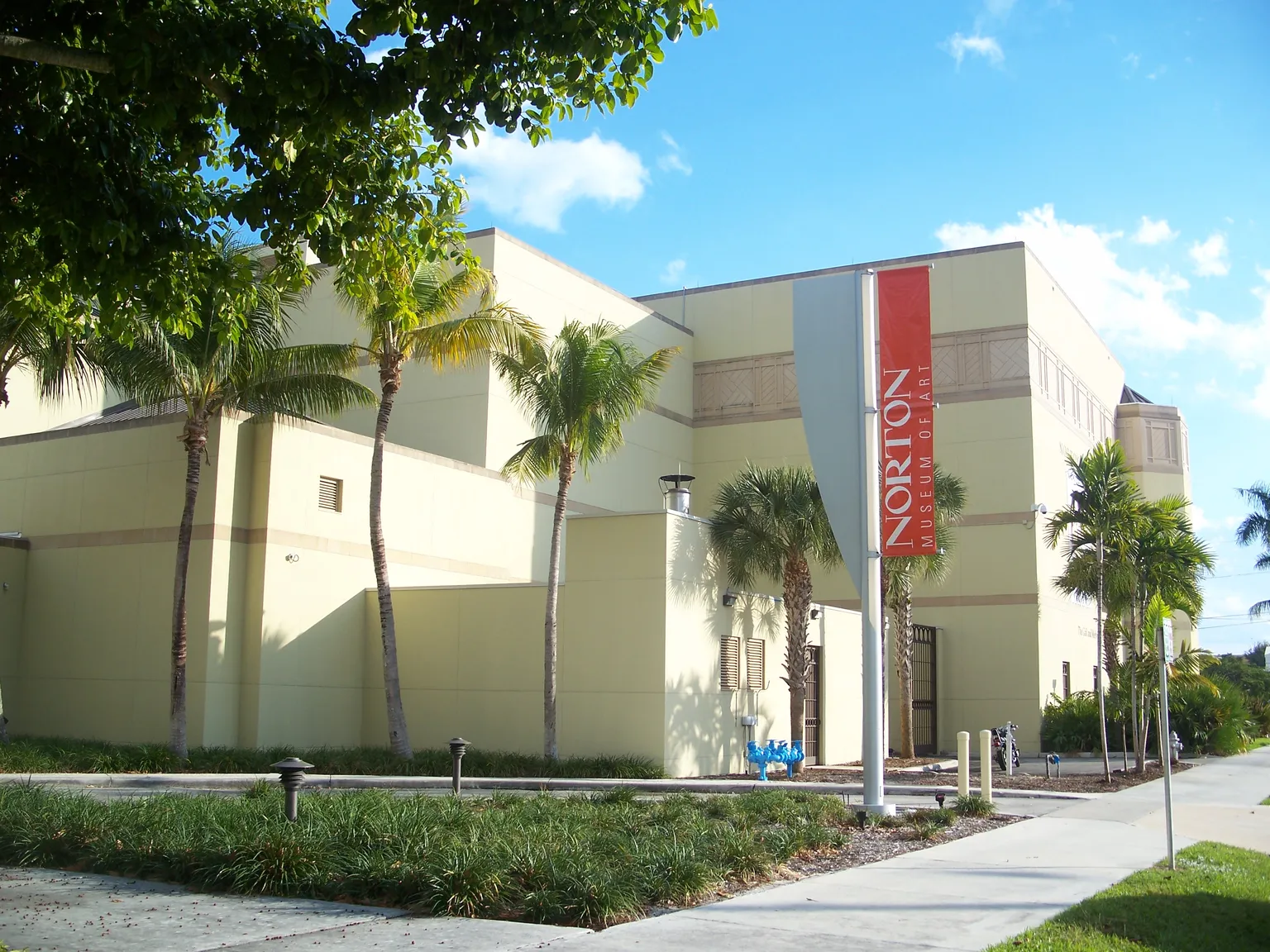 The Norton Museum of Art building in West Palm Beach, framed by palms and a tree canopy.
