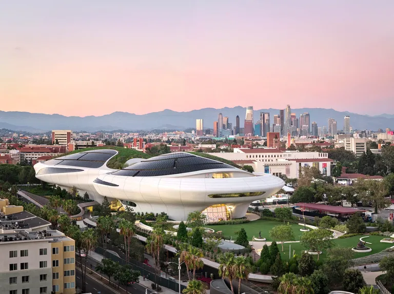 Aerial view of the Lucas Museum of Narrative Art in Exposition Park with Los Angeles skyline behind it.