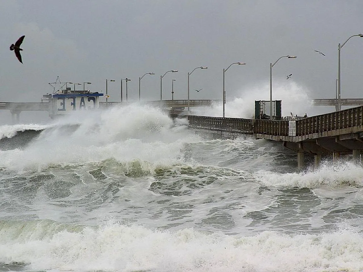 Storm waves crash against a pier, illustrating the coastal-weather risks associated with a strengthening El Niño
