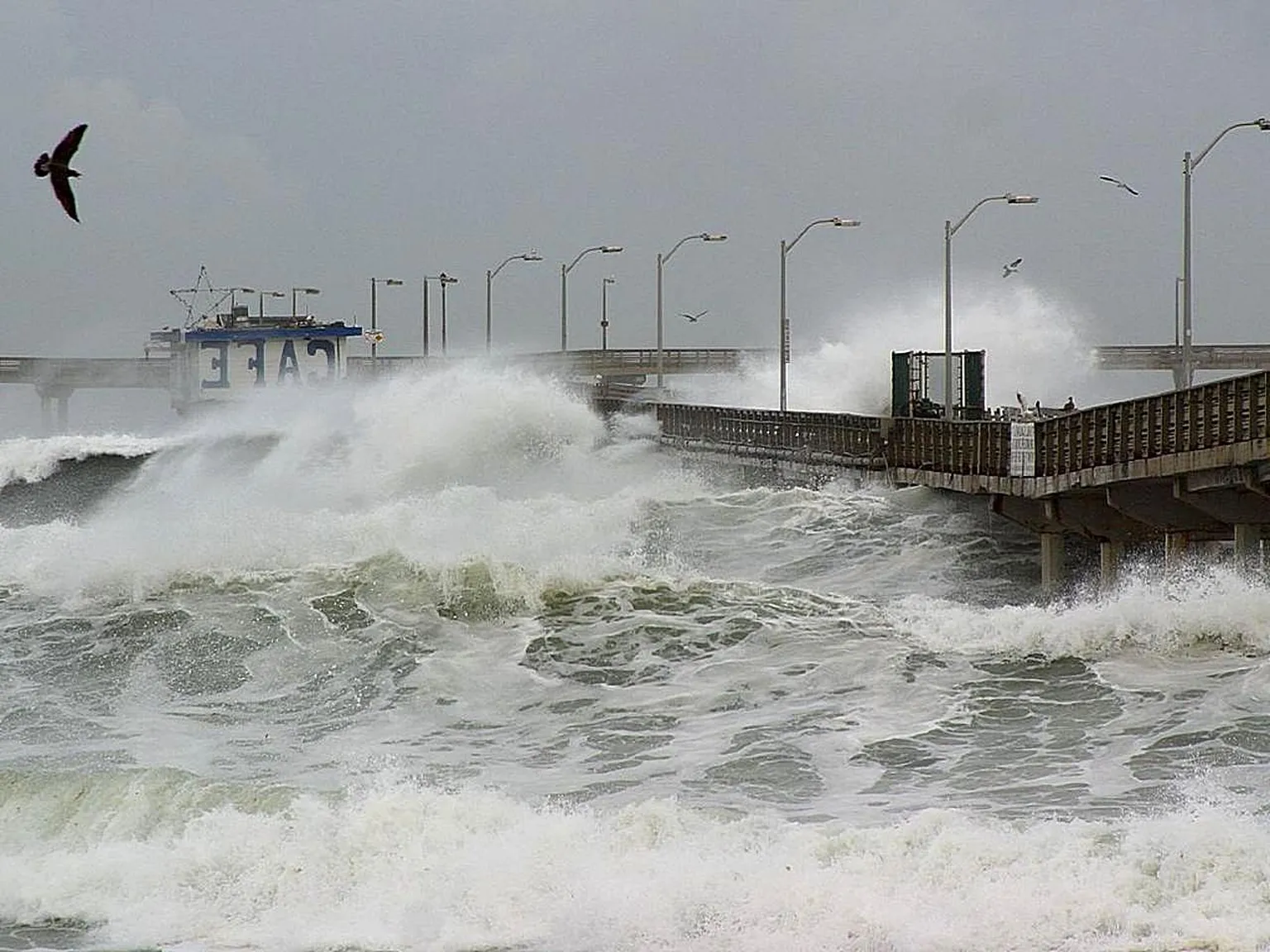 Storm waves crash against a pier, illustrating the coastal-weather risks associated with a strengthening El Niño