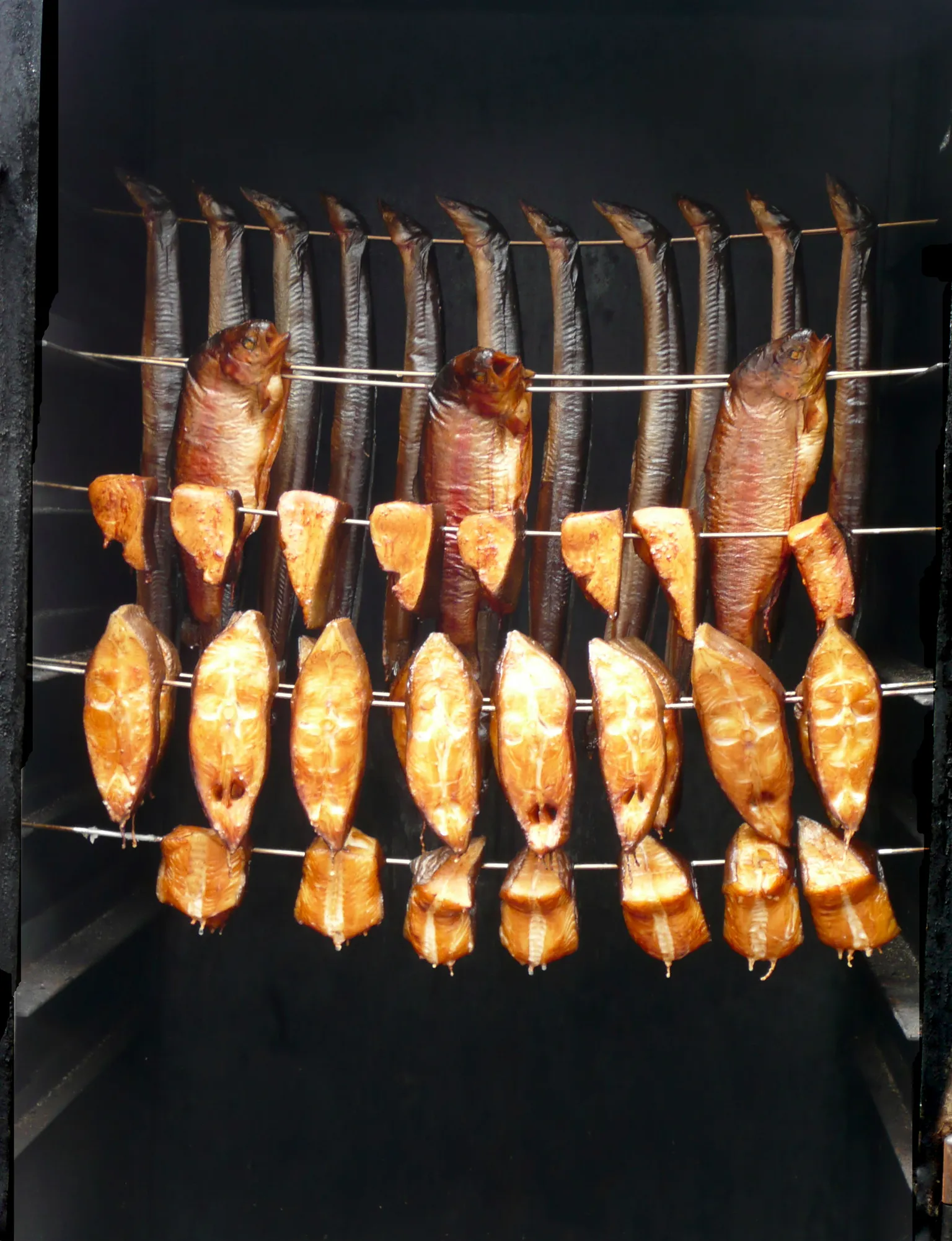 Several smoked fish hanging inside a smoker; illustrative image, not the recalled Haifa sprats.
