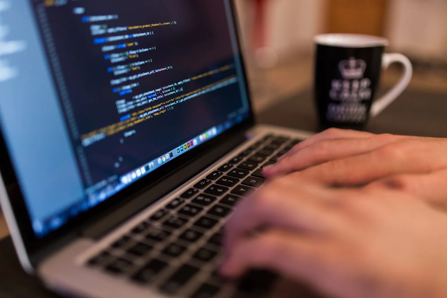 A person types on a laptop displaying lines of code.