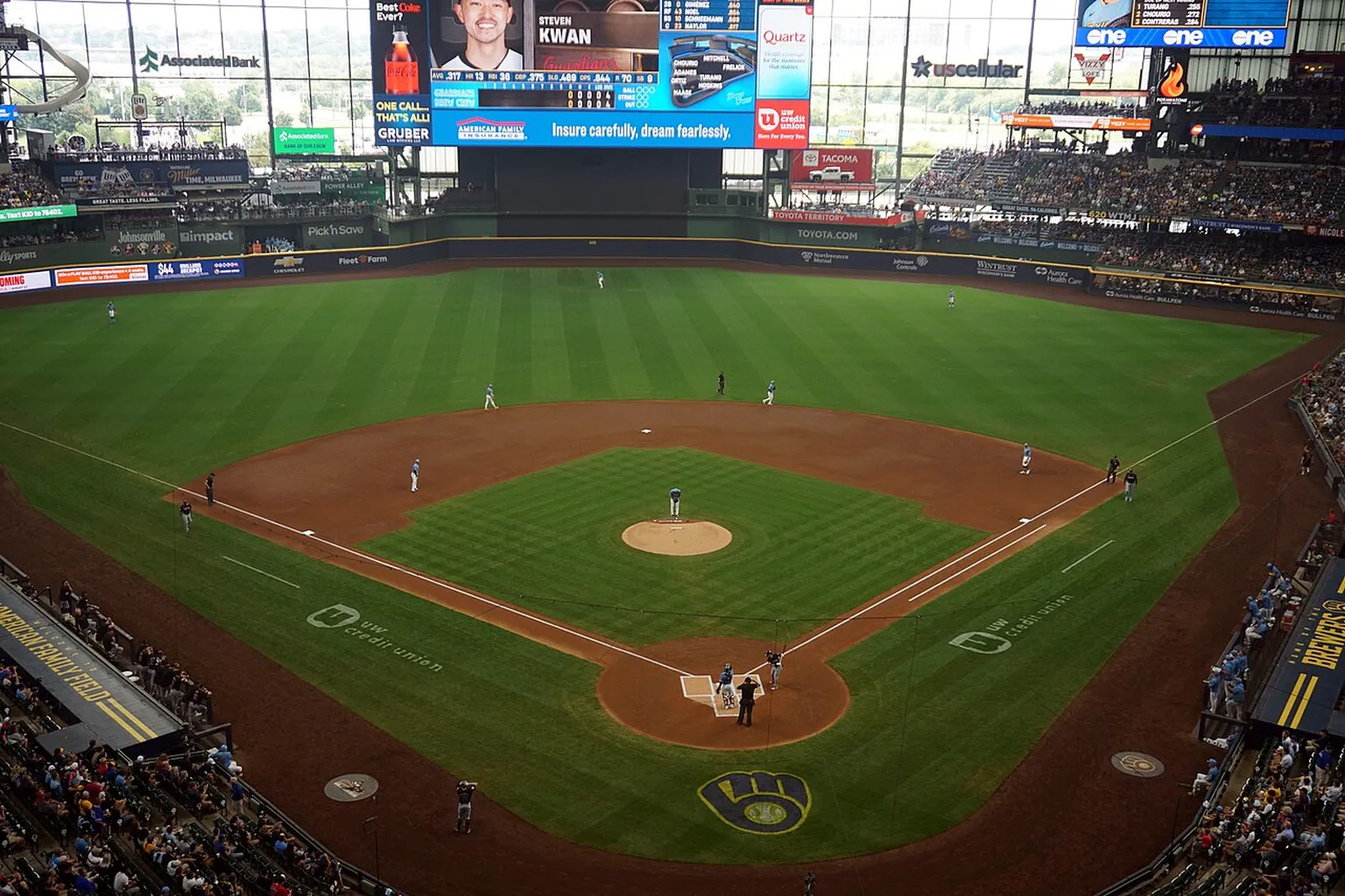 American Family Field during a Brewers–Guardians game, viewed from behind home plate with players on the field.